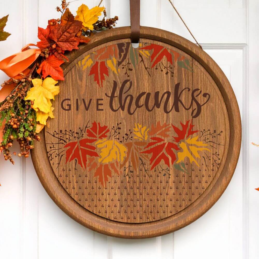 Decorative stencil round sign with 'Give Thanks' and colorful autumn leaves for Thanksgiving décor.